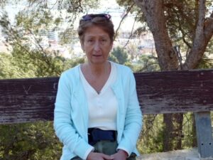 Janice smiling and sitting on a bench.