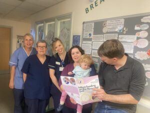 Family of baby who co-designed infant feeding booklet for NICU parents with NICU nurses. Dad is holding the booklet.