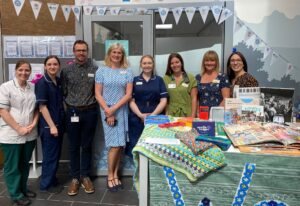 Eight members of the NNUH dementia support team standing in a line in front of their information stand