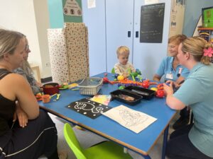 Play team in the play room with a toddler and his parent.